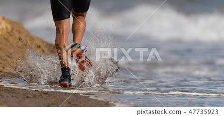 Athlete runner running on waves of sea beach Athlete runner running on waves of sea beach 47735923