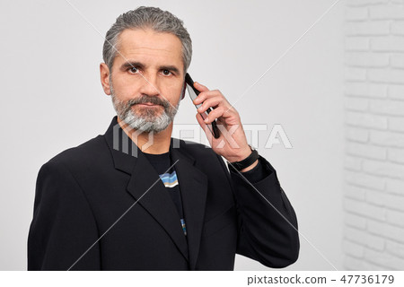 Serious man looking at camera, holding phone. Serious man looking at camera, holding phone. 47736179