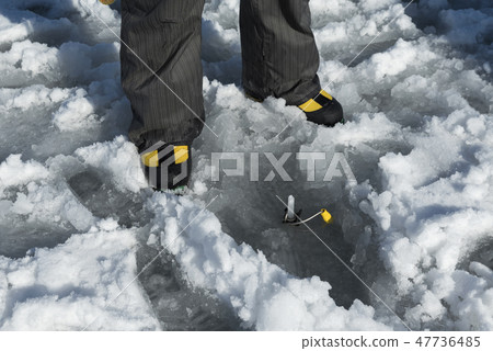 Yellow shoes and yellow ice screw drill in a lake  47736485