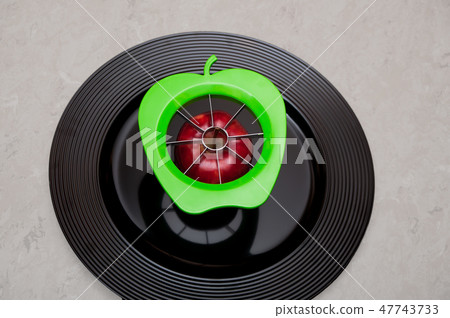 Green modern apple cutter with an apple on a plate Green modern apple cutter with an apple on a plate 47743733