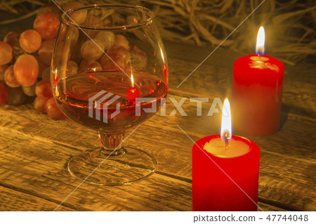 Glass with Cognac or Brandy, fresh grapes and candles. still life in rustic style, vintage wooden 47744048