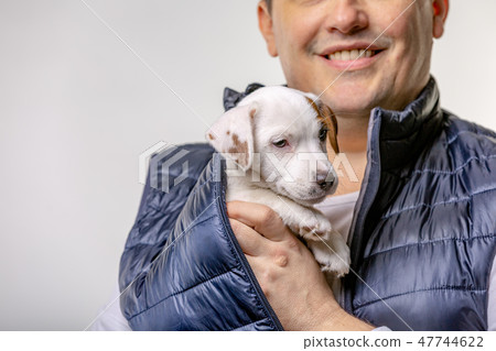 Horizontal portrait of handsome cheerful man holds jack russell terrirer, has glad expression 47744622