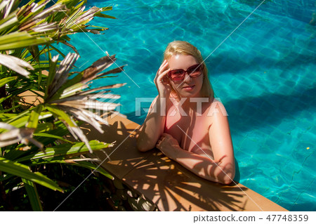 Young blonde beautiful woman in sunglasses in swimming pool Young blonde beautiful woman in sunglasses in swimming pool 47748359