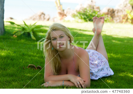 Young blonde beautiful woman laying at grass lawn in summer sexy dress Young blonde beautiful woman laying at grass lawn in summer sexy dress 47748360