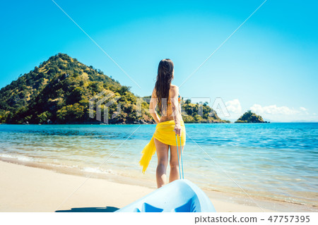 Woman dragging her boat to the water on the beach 47757395