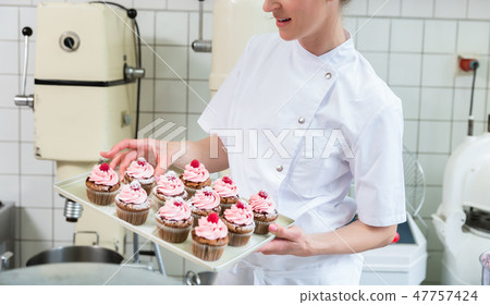 Baker women in pastry bakery working on muffins Baker women in pastry bakery working on muffins 47757424