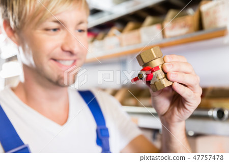 Hands of a worker holding two pipe fitting accessories in a sanitary shop Hands of a worker holding two pipe fitting accessories in a sanitary shop 47757478