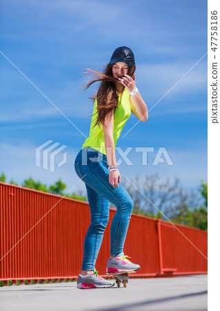 Teen girl skater riding skateboard on street. Teen girl skater riding skateboard on street. 47758186