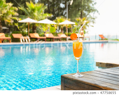 Orange juice glass with swimming pool background Orange juice glass with swimming pool background 47758655