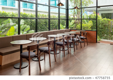 Rows of wooden table and chair inside of glass Rows of wooden table and chair inside of glass 47758735