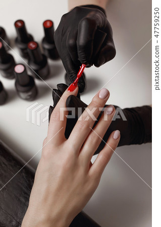 Manicurist in black gloves, causes the client Manicurist in black gloves, causes the client 47759250
