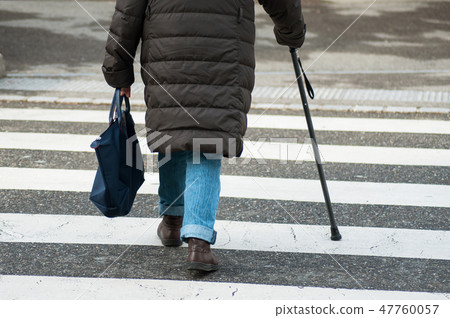 aged woman walking with stick in the street aged woman walking with stick in the street 47760057
