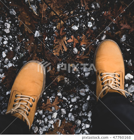 Feet of traveler in boots standing on ground Feet of traveler in boots standing on ground 47760168