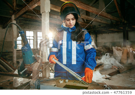 Woman wearing helmet using male work tools Woman wearing helmet using male work tools 47761359