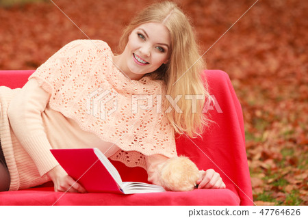 Woman relaxing in autumn fall park reading book. Woman relaxing in autumn fall park reading book. 47764626