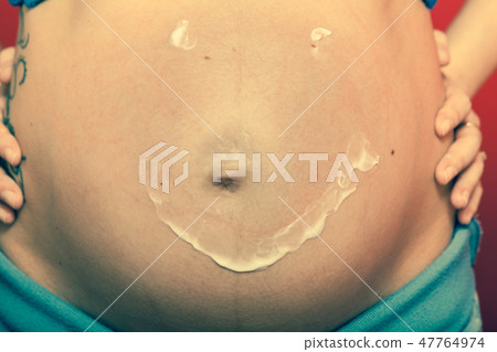 Pregnant woman having cream on big belly Pregnant woman having cream on big belly 47764974