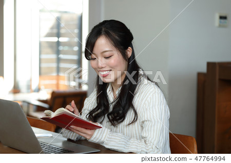 A woman looking at a notebook and thinking about a schedule 47764994