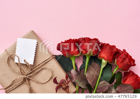 Something special for her: bouquet of fresh red roses and homemade gift in kraft wrapping paper 47765129