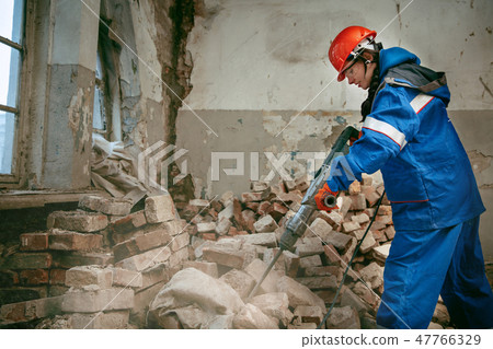 Woman wearing helmet using male work tools Woman wearing helmet using male work tools 47766329