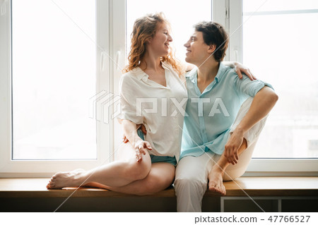 Happy girl and man hugging near window in home. Happy girl and man hugging near window in home. 47766527