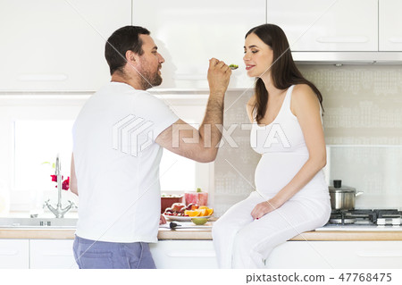 Pregnant woman and happy man in the kitchen 47768475