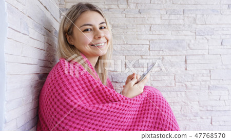 Pretty girl sitting on the window sill with smartphone in hands. 47768570