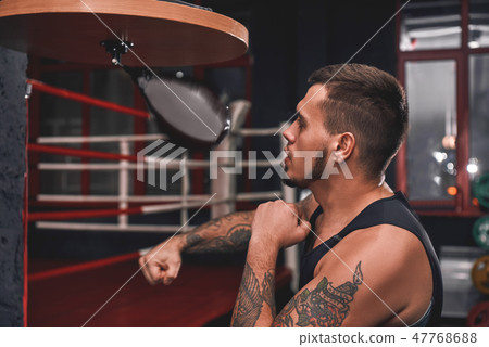 Ready to break his record. Close-up of muscular tattooed boxer in sports clothing hitting punching 47768688