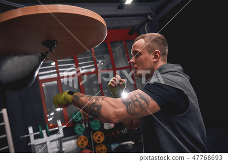 Stay strong to win. Side view of professional young boxer with green hands bandages hitting punching Stay strong to win. Side view of professional young boxer with green hands bandages hitting punching 47768693