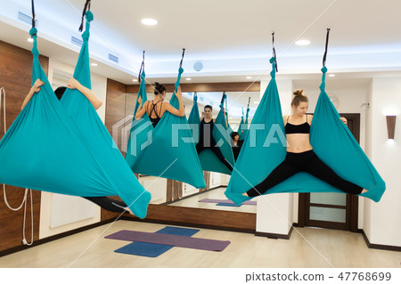 Women doing fly yoga stretching exercises in hammo Women doing fly yoga stretching exercises in hammo 47768699
