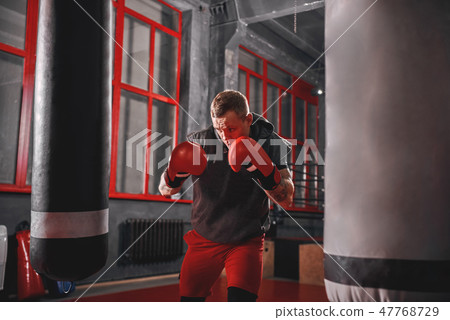 Impossible is Nothing. Muscular sportsman in sport clothing exercising on heavy punch bag before Impossible is Nothing. Muscular sportsman in sport clothing exercising on heavy punch bag before 47768729