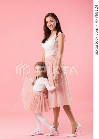 charming mother and smiling daughter on pink background 47769124