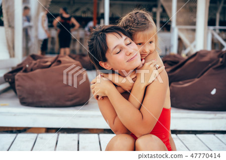 Young mother giving daughter piggyback ride on the beach 47770414