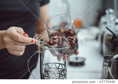 Pour dry tea leaves into the glass container of the tea press maker Pour dry tea leaves into the glass container of the tea press maker 47770440
