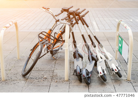Bicycle and electric scooters parked on city street. Self-service street transport rental service Bicycle and electric scooters parked on city street. Self-service street transport rental service 47771046