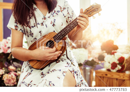 Happy woman musician playing ukulele in studio. 47773783
