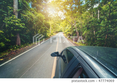 Side view of car driving on road in forest highway Side view of car driving on road in forest highway 47774069