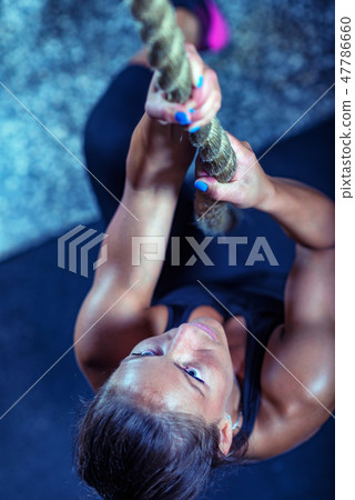 Woman athlete exercising on gymnastic rings Woman athlete exercising on gymnastic rings 47786660