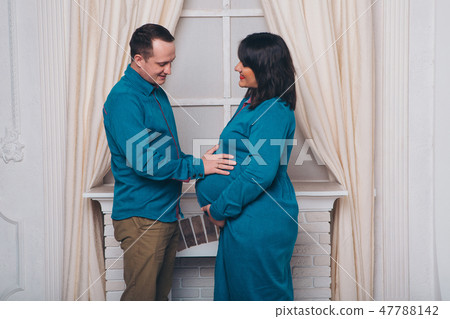 the husband embraces the pregnant wife on a white 47788142