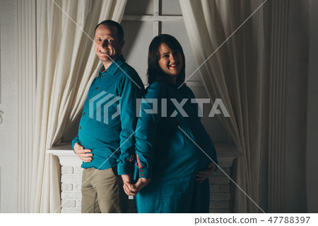 Family portrait: the husband embraces the pregnant wife on a white background. pregnant couple in 47788397