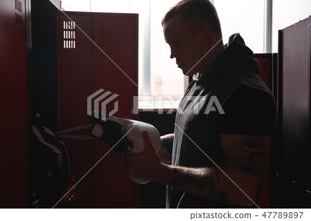 Training to become the best. Muscular young boxer looking at boxing gloves while preparing for Training to become the best. Muscular young boxer looking at boxing gloves while preparing for 47789897