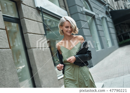 Fashion. Young stylish woman walking on the city street looking down laughing playful Fashion. Young stylish woman walking on the city street looking down laughing playful 47790221