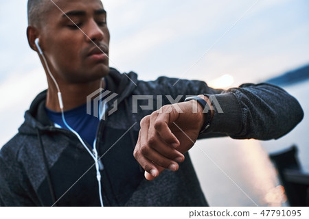 Young african model looks at his smartwatch to track distance what he had run 47791095