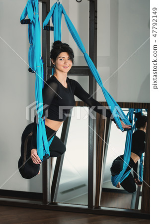 Yoga in a white room. woman performs physical exercises fly-yoga, pilates on a special equipment Yoga in a white room. woman performs physical exercises fly-yoga, pilates on a special equipment 47792149