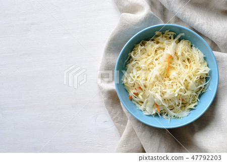 Blue bowl with sauerkraut on a white table 47792203