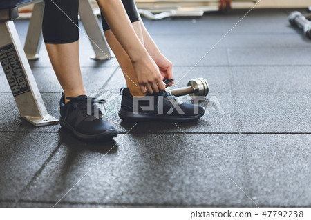 A young lady tying a shoelace at the gym 47792238