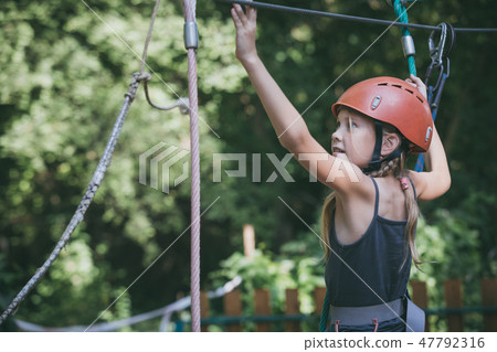 little girl make climbing in the adventure park. 47792316