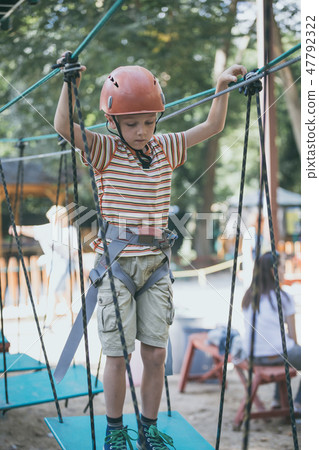 little boy make climbing in the adventure park. 47792322