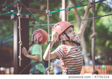 little boy make climbing in the adventure park. 47792328