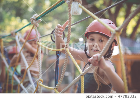 little brother and sister make climbing in the adventure park. 47792332
