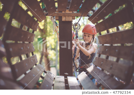 little brother and sister make climbing in the adventure park. 47792334